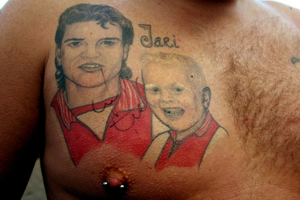 AMSTERDAM, NETHERLANDS - SEPTEMBER 9: Mike Weermeier displays a chest tattoo of Finnish soccer player Jari Litmanen (L) on the first day of practice where he starts for a second season with Ajax September 9, 2002 in Amsterdam, Netherlands. The child depicted to the left is Mike's eight-year-old son, Jari, who is named after idol Litmanen, who was transferred from Liverpool and is immensely popular in Holland. (Photo by Michel Porro/Getty Images)