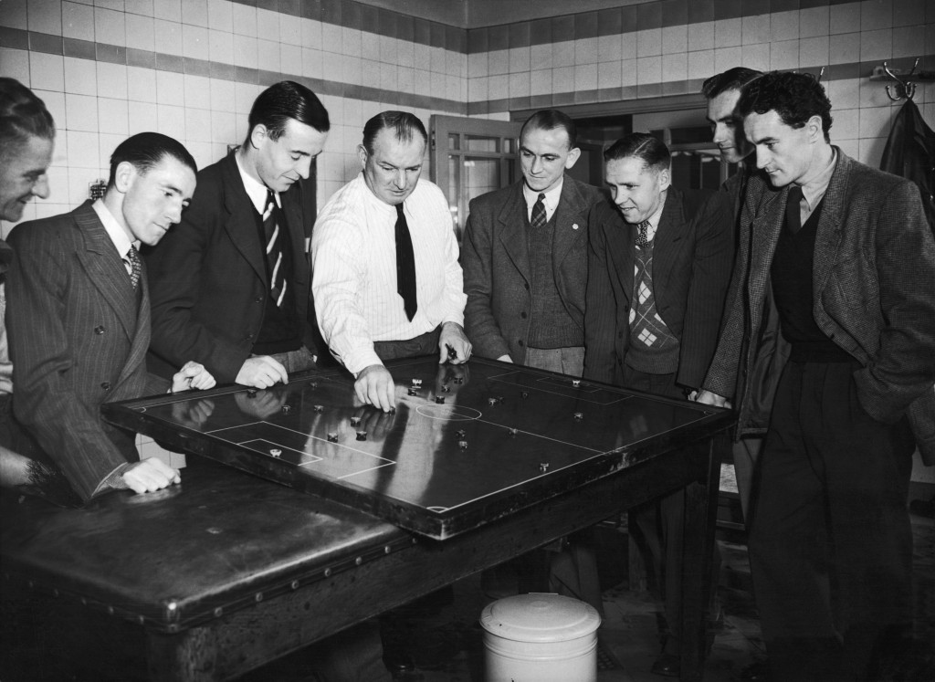 Arsenal manager Tom Whittaker demonstrating a plan on the tactics table during a meeting with the team in the dressing room at Highbury Stadium, North London, 31st January 1947. From left to right Jimmy Logie, Reginald Lewis, Ernest Collett, Laurie Scott and Joshua Sloan.(Photo by Central Press/Getty Images)