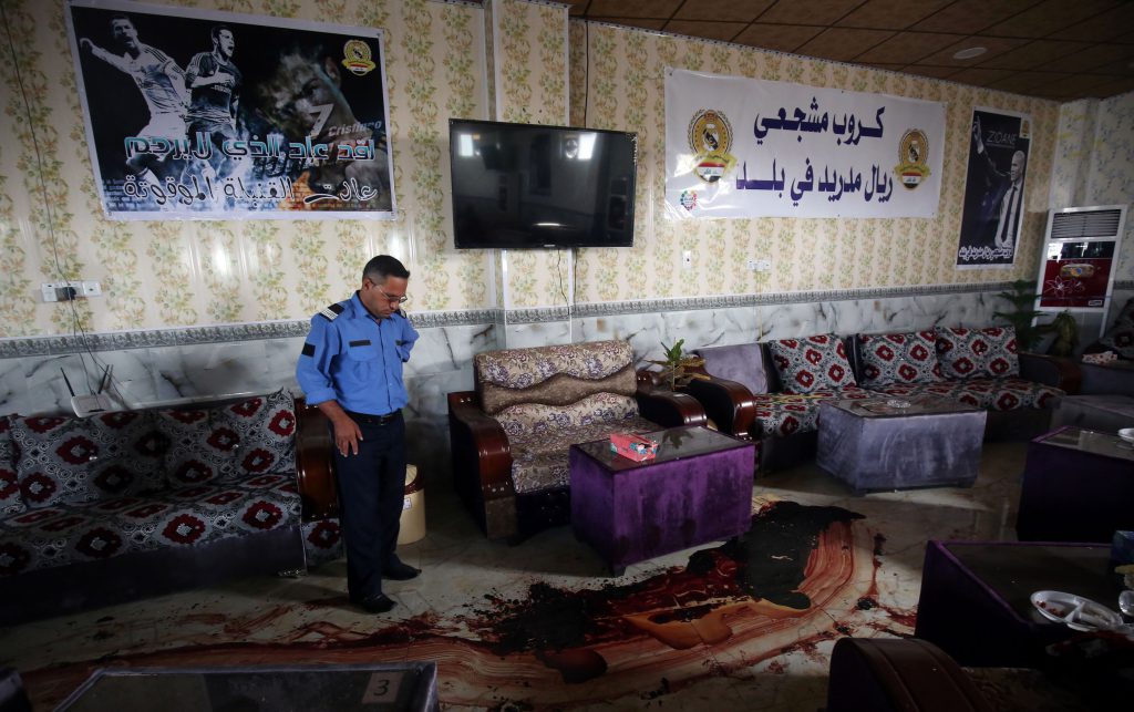 An Iraqi policeman stands over a trail of blood and debris at a cafe, that was popular with local fans of Spain's Real Madrid football club, in the Balad area, north of the capital Baghdad, on May 14, 2016, a day after a deadly raid claimed by Islamic State group militants. At least 16 people were killed and 30 wounded, including several members of the security forces, in the attack in the town of Balad and the ensuing chase, officials said. / AFP / AHMAD AL-RUBAYE (Photo credit should read AHMAD AL-RUBAYE/AFP/Getty Images)