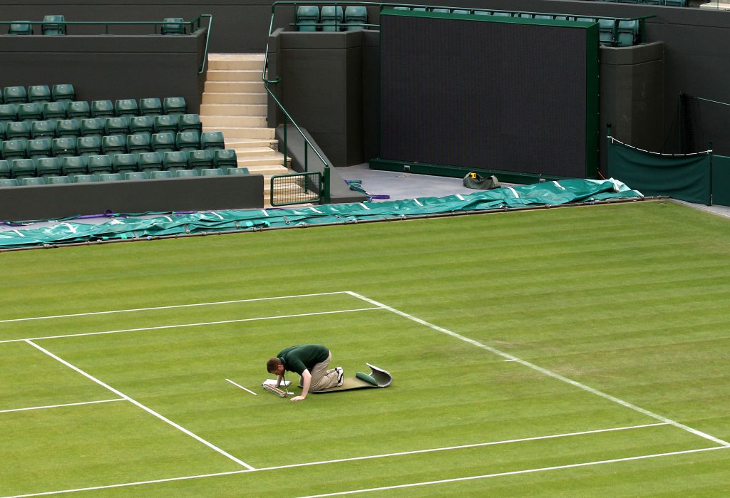 LONDON, ENGLAND - JUNE 22: A worker checks the grass on Day Three of the Wimbledon Lawn Tennis Championships at the All England Lawn Tennis and Croquet Club on June 22, 2011 in London, England. (Photo by Oli Scarff/Getty Images)