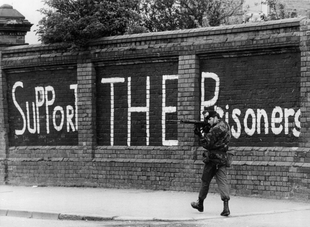 13th May 1981: A British soldier looking out for snipers as he patrols the Falls Road in Belfast. The graffiti in the background is in support of Bobby Sands and his fellow hunger-strikers. (Photo by Rob Taggart/Central Press/Getty Images)