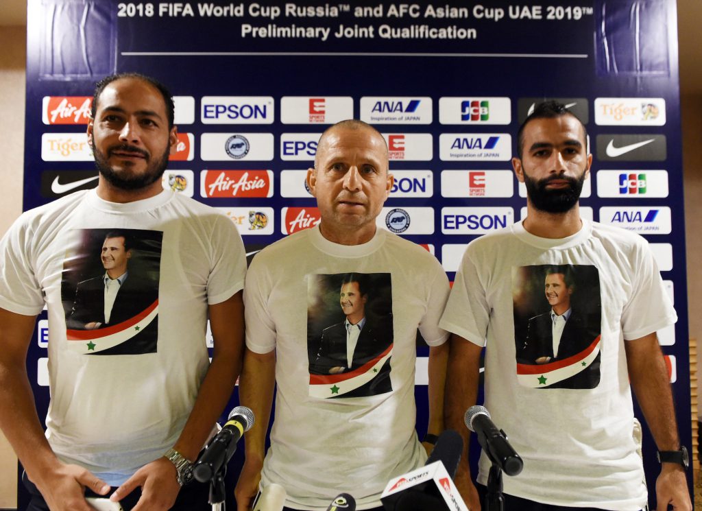 Il ct Fajr Ibrahim (C) e due giocatori con una t-shirt di Assad prima della partita di qualificazione contro Singapore, novembre 2016 (Roslan Rahman/Afp/Getty Images)