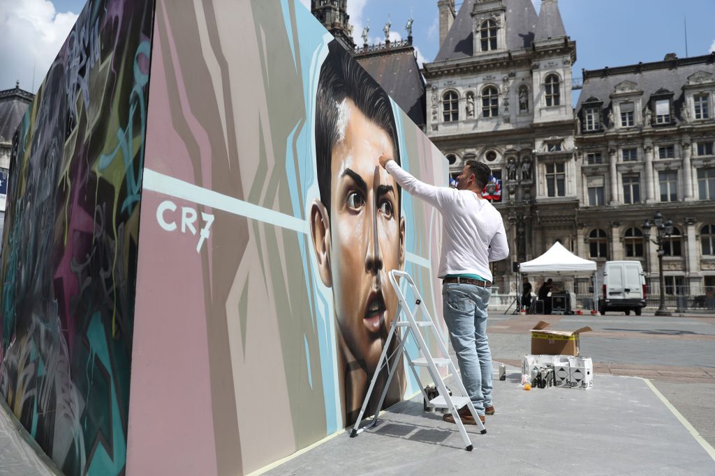 An artist paints a picture of Portugal's forward Cristiano Ronaldo for an exhibition in front of the Hotel de Ville city hall in Paris on June 7, 2016, ahead of the start of the Euro 2016 football tournament. / AFP / KENZO TRIBOUILLARD / RESTRICTED TO EDITORIAL USE - TO ILLUSTRATE THE EVENT AS SPECIFIED IN THE CAPTION (Photo credit should read KENZO TRIBOUILLARD/AFP/Getty Images)