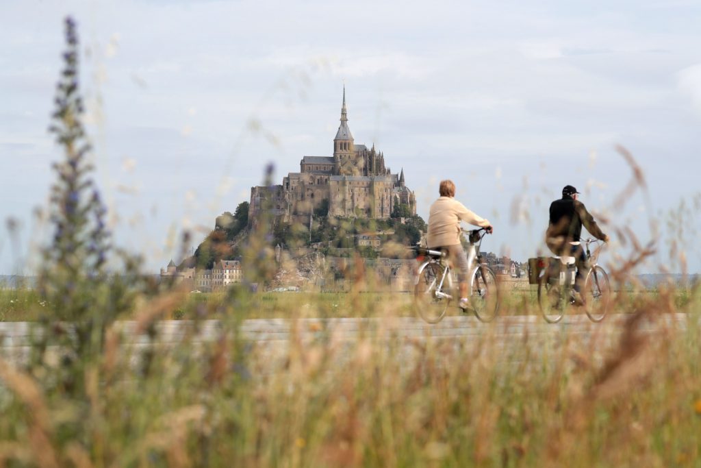 A couple rides past Le Mont-Saint-Michel, on June 29, 2016, three days before the start of the 103rd edition of the Tour de France cycling race. The 2016 Tour de France will start on July 2 in the streets of Le Mont-Saint-Michel and ends on July 24, 2016 down the Champs-Elysees in Paris. / AFP / KENZO TRIBOUILLARD (Photo credit should read KENZO TRIBOUILLARD/AFP/Getty Images)