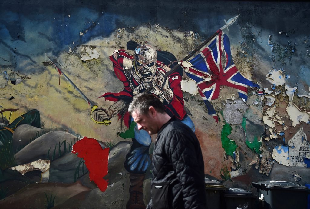 LONDONDERRY, NORTHERN IRELAND - MAY 04: A man walks past a mural marking unionist territory on May 4, 2016 in Londonderry, Northern Ireland. The city of Londonderry is situated on the border between the north and south of Ireland. Flags, murals or kerbstone painting are sometimes the first visual indication of the border having been crossed. The United Kingdom has just one external land border which is located between Northern Ireland and the Republic of Ireland. At present there are no checkpoints in place for anyone crossing this border, either by foot or vehicle. Prior to the Anglo-Irish agreement anyone wishing to cross the border was subjected to armed checkpoints while unguarded country roads were blocked by concrete barricades. With the Brexit referendum taking place on June 23 to decide whether Britain should remain in the European Union some politicians have warned that the open border could be used as a possible backdoor entrance by migrants, traffickers and criminals wishing to gain access to the UK following a decision to leave the EU. (Photo by Charles McQuillan/Getty Images)