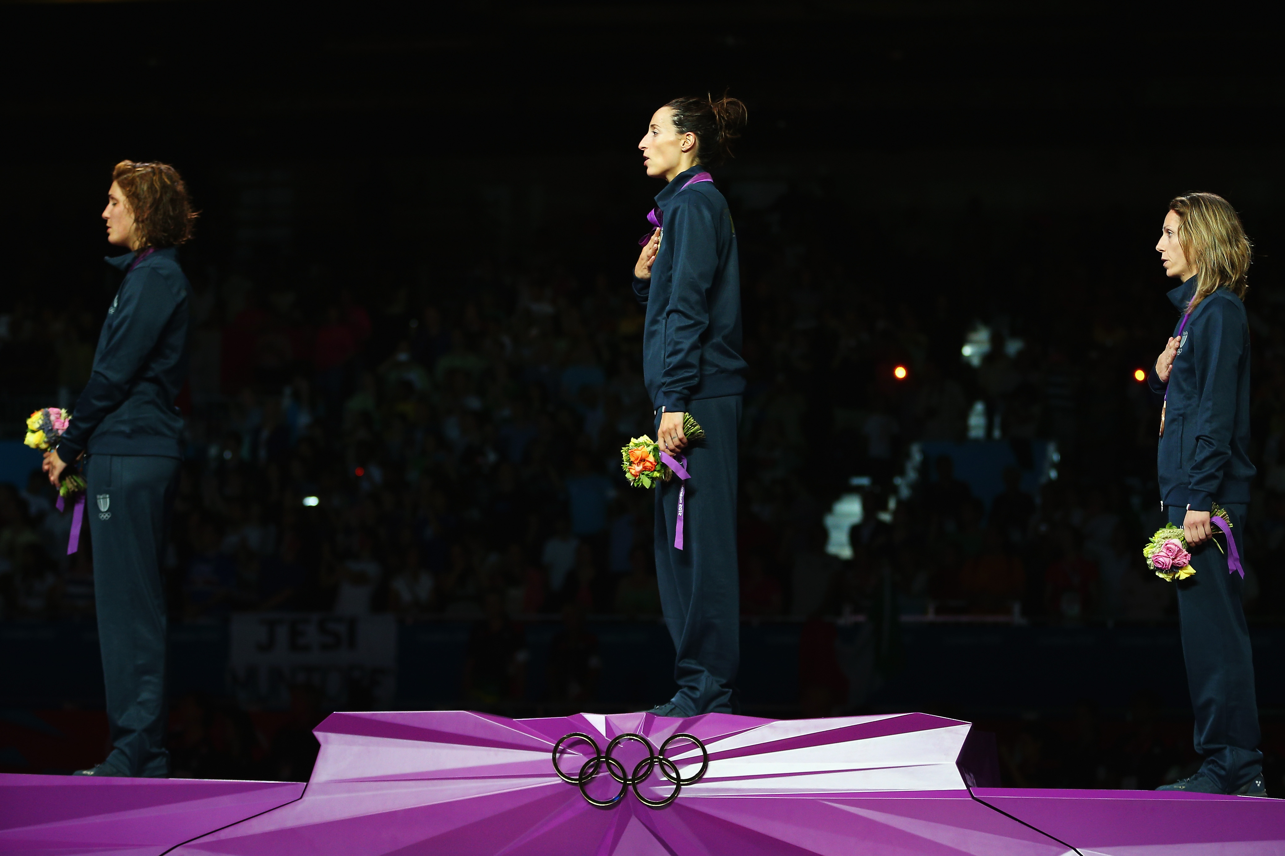 LONDON, ENGLAND - JULY 28: Arianna Errigo, Elisa Di Francisca and Valentina Vezzali of Italy sing the national anthem after receiving their medals after competing in the Women's Foil Individual Fencing matches on Day 1 of the London 2012 Olympic Games at ExCeL on July 28, 2012 in London, England. (Photo by Hannah Peters/Getty Images)