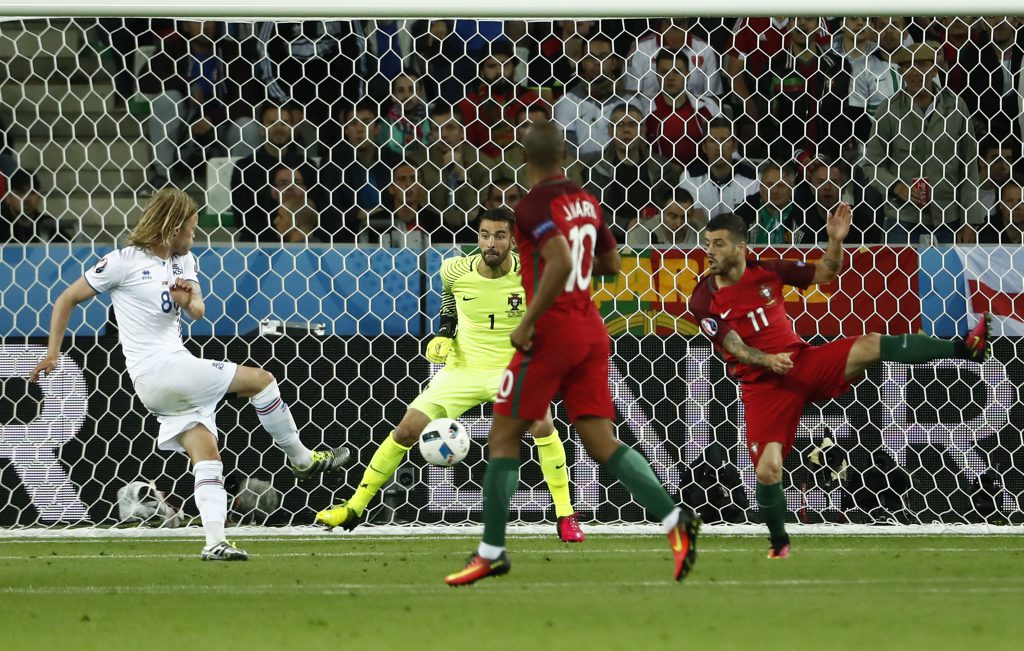 TOPSHOT - Iceland's midfielder Birkir Bjarnason (L) shoots the ball to score a goal against Portugal's goalkeeper Rui Patricio (2nd L) during the Euro 2016 group F football match between Portugal and Iceland at the Geoffroy-Guichard stadium in Saint-Etienne on June 14, 2016. / AFP / ODD ANDERSEN (Photo credit should read ODD ANDERSEN/AFP/Getty Images)