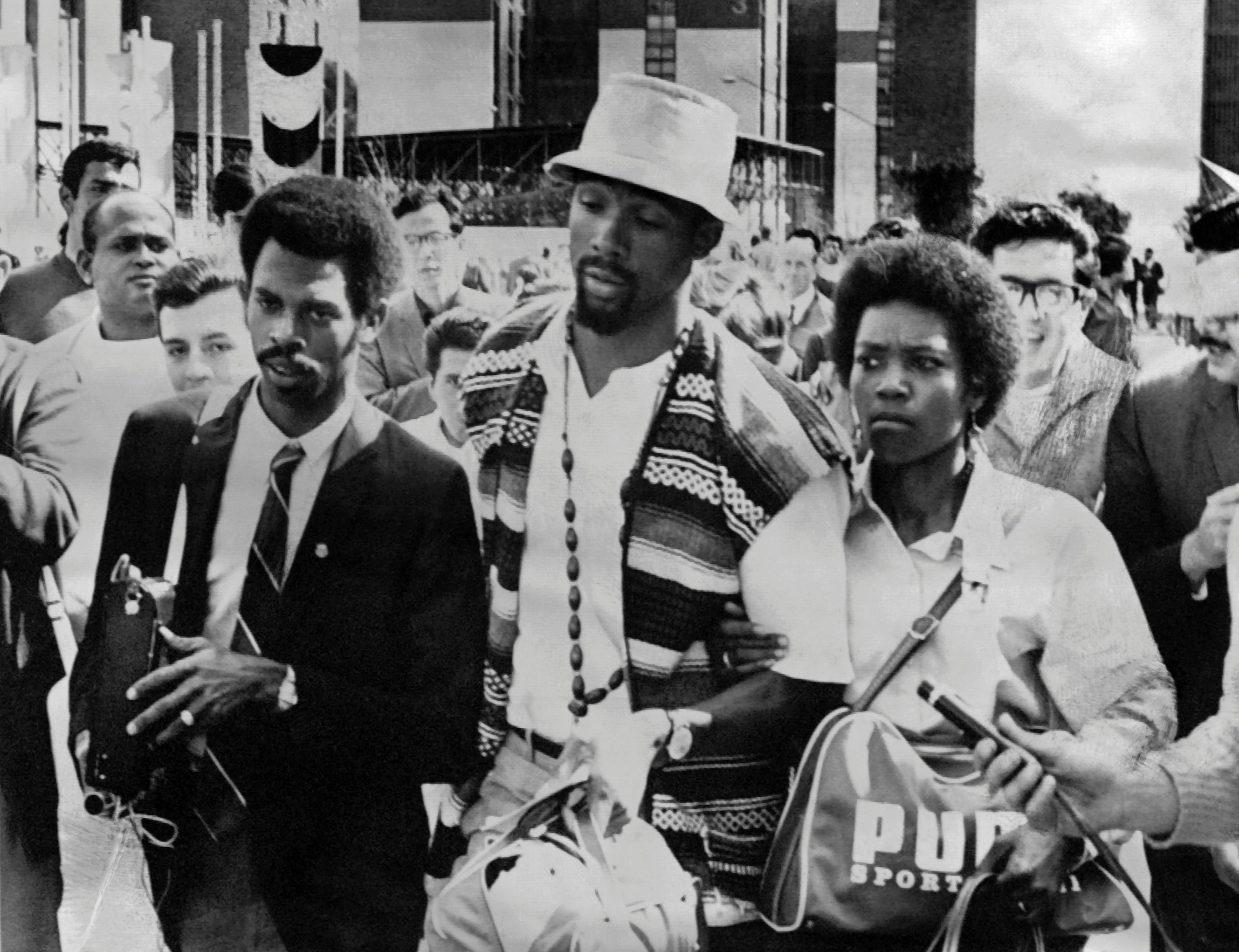 US sprinter John Carlos (C) leaves the Olympic village with his wife, after being suspended, along with his teammate Tommie Smith, from his national team and banned from the Olympic Village, because of the victory ceremony demonstration during the Mexico 1968 Olympic Games on October 18, 1968, in Mexico City. After having received their medals 17 October 1968 for first and third place in the 200 metres event, US athletes Tommie Smith and John Carlos raised their gloved fists in the Black Power salute to express their opposition to racism in the USA. / AFP / EPU / - (Photo credit should read -/AFP/Getty Images)