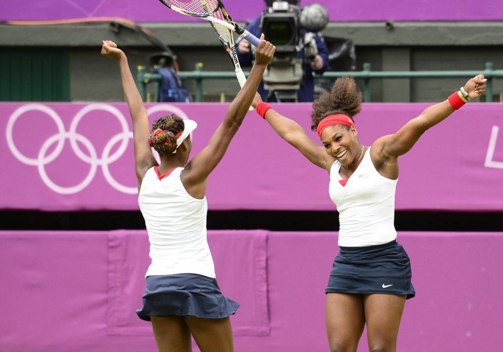 US Venus Williams (L) and Serena Williams celebrate after winning the women's doubles gold medal match of the London 2012 Olympic Games by defeating Czech Republic's Andrea Hlavackova and Lucie Hradecka, at the All England Tennis Club in Wimbledon, southwest London, on August 5, 2012. AFP PHOTO / LEON NEAL        (Photo credit should read LEON NEAL/AFP/GettyImages)