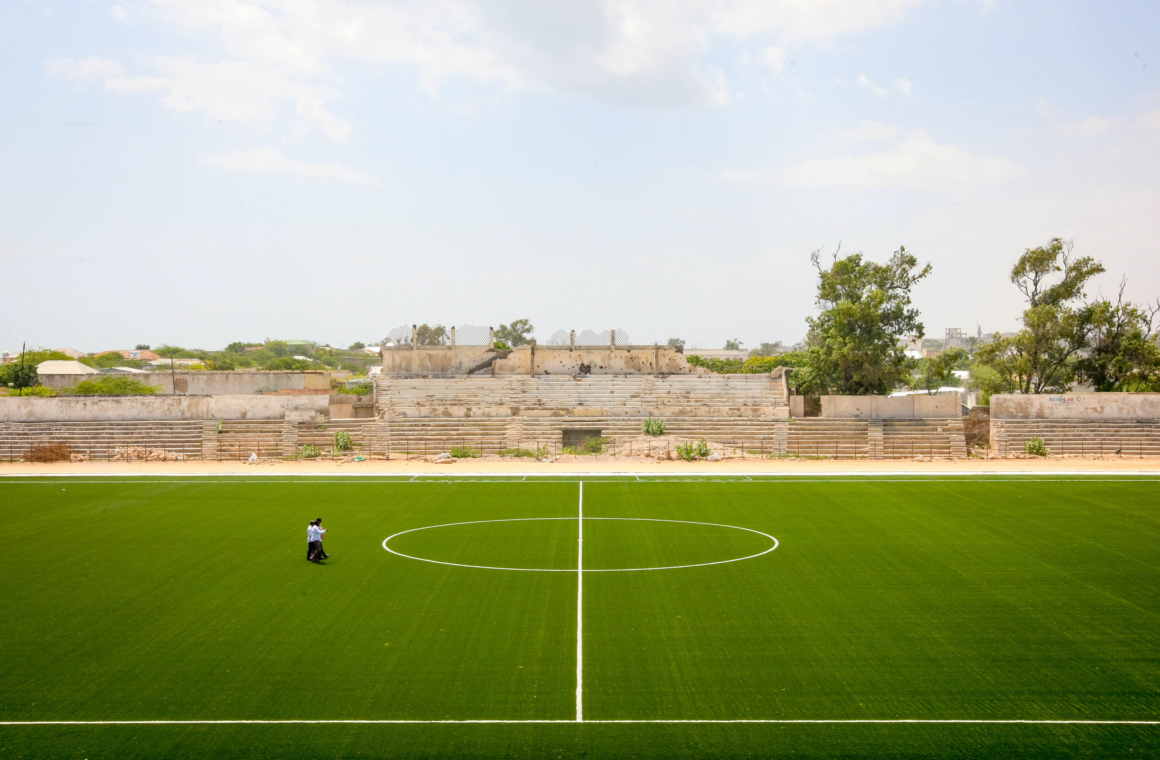 A handout photograph taken on January 12, 2013 and released on January 16 by the African Union-United Nations Information Support Team, shows members of the Somali Football Federation (SFF) walking across the football pitch inside Baanadir Stadium in the Abd-Aziz District of the Somali capital Mogadishu. The field that has recently been re-surfaced with a new artificial playing surface funded by FIFA, the SFF with repair work to begin on the seats, parking and facilities of the 7,500-capacity stadium. After two decades of near-constant conflict, Somalia is enjoying its longest period of peace and growing security since the Al-Qaeda-allied violent extremist group Al Shabaab was driven from Mogadishu in August 2011. Under the Shabaab's draconian rule, social pastimes and sports such as football were banned but residents of the city and elsewhere across Somalia. AFP PHOTO / AU-UN IST PHOTO / STUART PRICE /HO (Photo credit should read STUART PRICE/AFP/Getty Images)