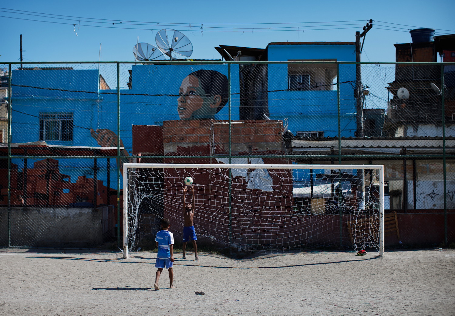 RIO DE JANEIRO, BRAZIL - JUNE 29: Kids play football at the Vila Cruzeiro favela on June 29, 2013 in Rio de Janeiro, Brazil. It was at the end of 2010 that under the stage of pacification some 300 police officers went into the Complexo do Alemao with tanks and helicopters to drive out the criminal gangs to establish a permanent police presences and to set up social services such as schools, healthcare centers, and rubbish collection. The Complexo do Alemao favela is, with a population of 100, 000 and stretching for more than 3 kilometers with a maze of narrow alleys and stairways, one of the largest favelas in Rio de Janeiro. (Photo by Jasper Juinen/Getty Images)