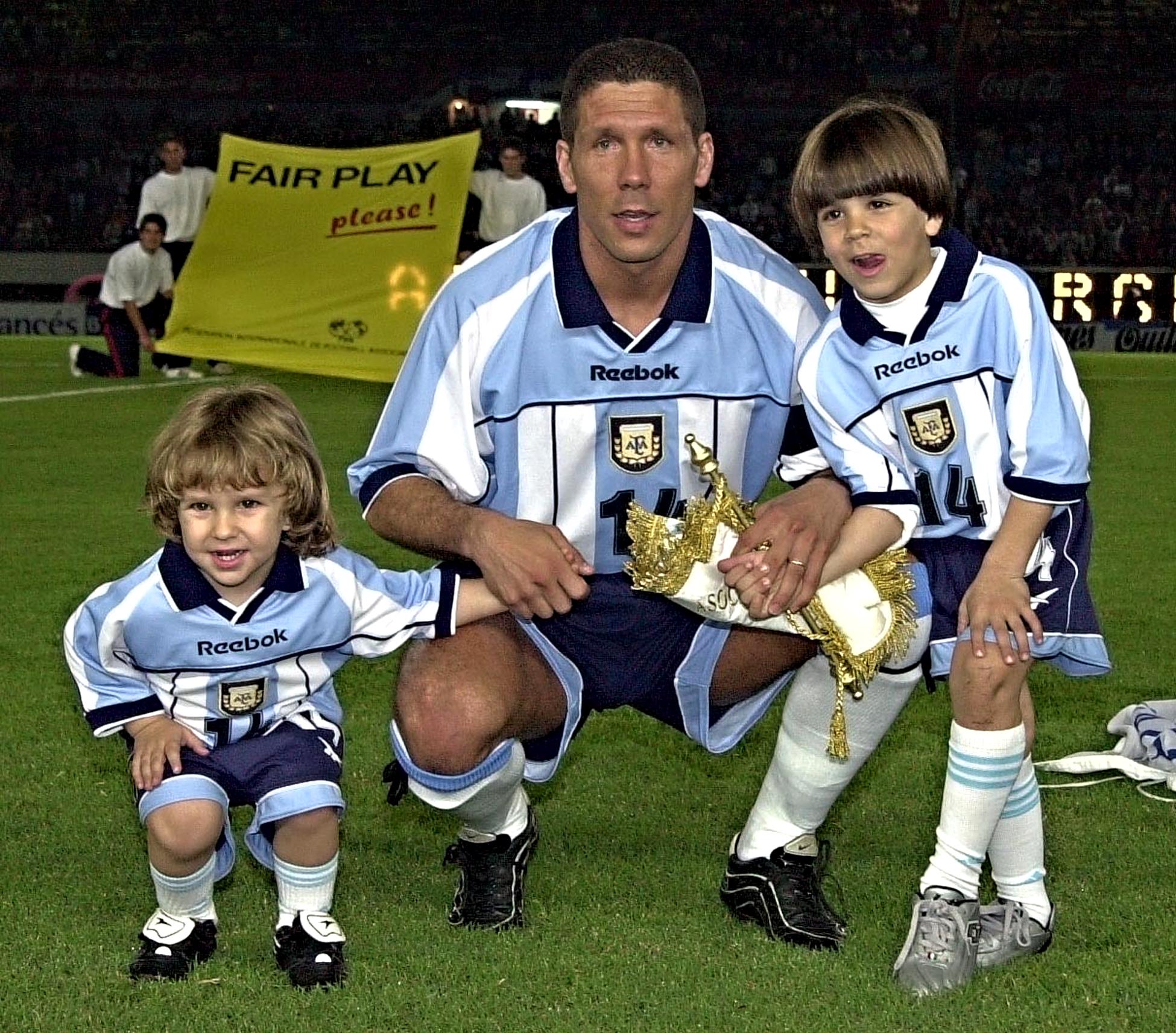 BUENOS AIRES, ARGENTINA - MARCH 28: Diego Simeone pauses with his children Giovanni (L) and Gianluca (R) after he received a silver plate for playing 100 matches for Argentina in the Monumental Stadium of Buenos Aires, Argentian, after a match against Venezuela for the Japan-Korea 2002 World Cup qualification. Diego Simeone posa con sus hijos Giovanni (I) y Gianluca (D) luego de recibir la placa recordatoria que le entregaron al cumplir cien partidos con la camiseta de la seleccion Argentina con el partido frente a Venezuela el 28 de marzo de 2001 en el estadio Monumental de la ciudad de Buenos Aires. Argentina vence 3-0 a Venezuela al promediar el segundo tiempo del partido por la decimoprimera fecha de las eliminatorias sudamericanas para la copa del mundo Corea-Japon 2002. (Photo credit should read MIGUEL MENDEZ/AFP/Getty Images)