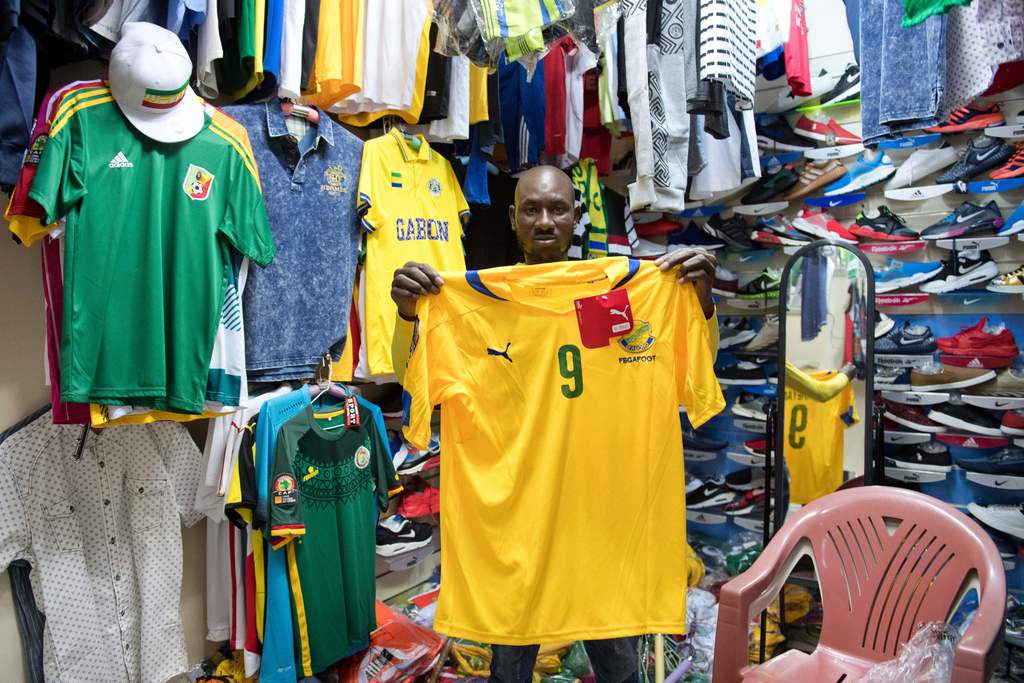 A man selling football shirts poses holding a Gabon team strip at a store in Port-Gentil on January 18, 2017, during the 2017 Africa Cup of Nations football tournament in Gabon. / AFP / Justin TALLIS (Photo credit should read JUSTIN TALLIS/AFP/Getty Images)