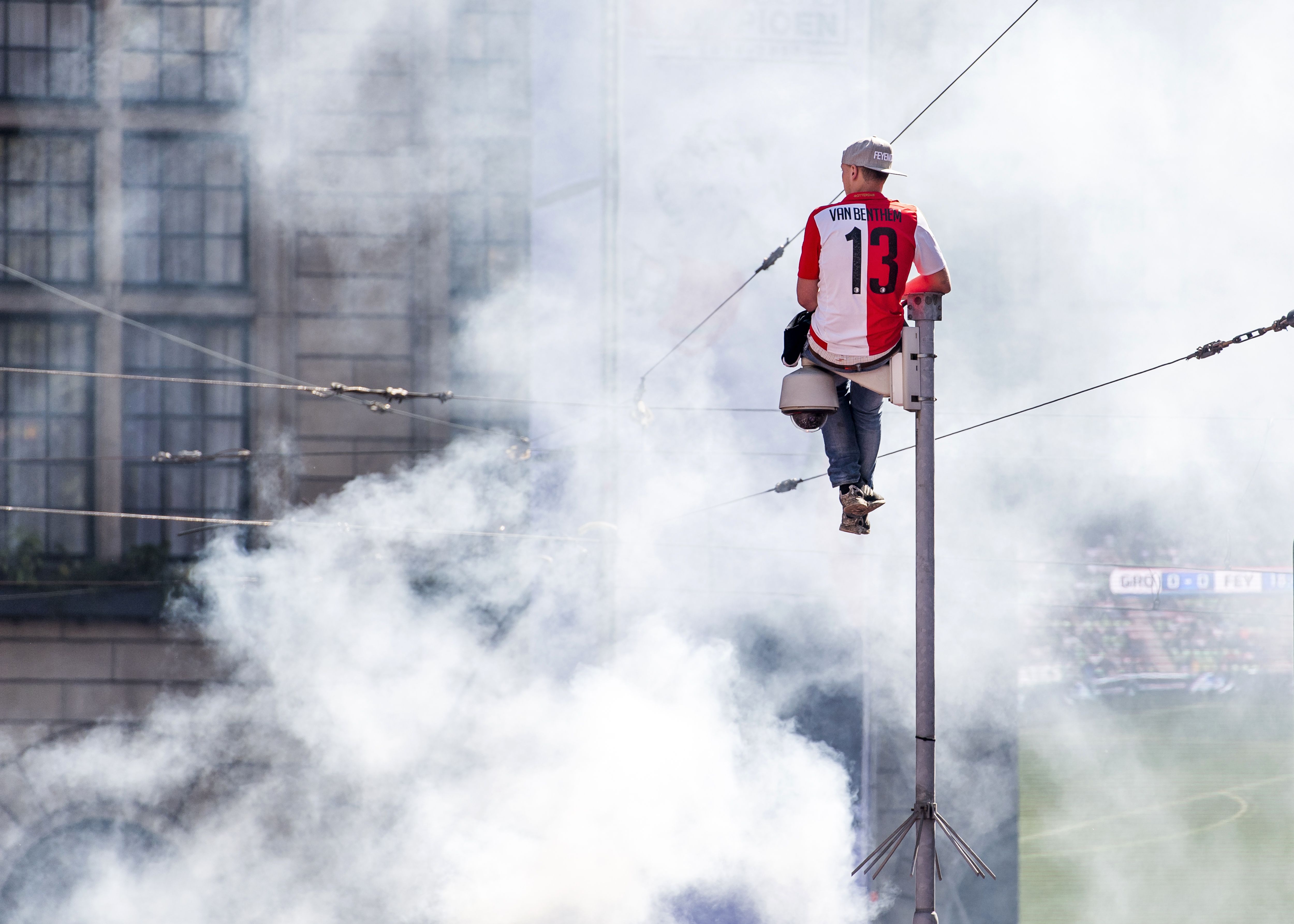 A Feyenoord Rotterdam supporter sits on top of a surveillance camera at the Coolsingel in Rotterdam on May 15, 2017, prior to celebrations by Feyenoord for winning the Netherlands' Eredevisie football division. / AFP PHOTO / ANP / Marco de Swart / Netherlands OUT (Photo credit should read MARCO DE SWART/AFP/Getty Images)