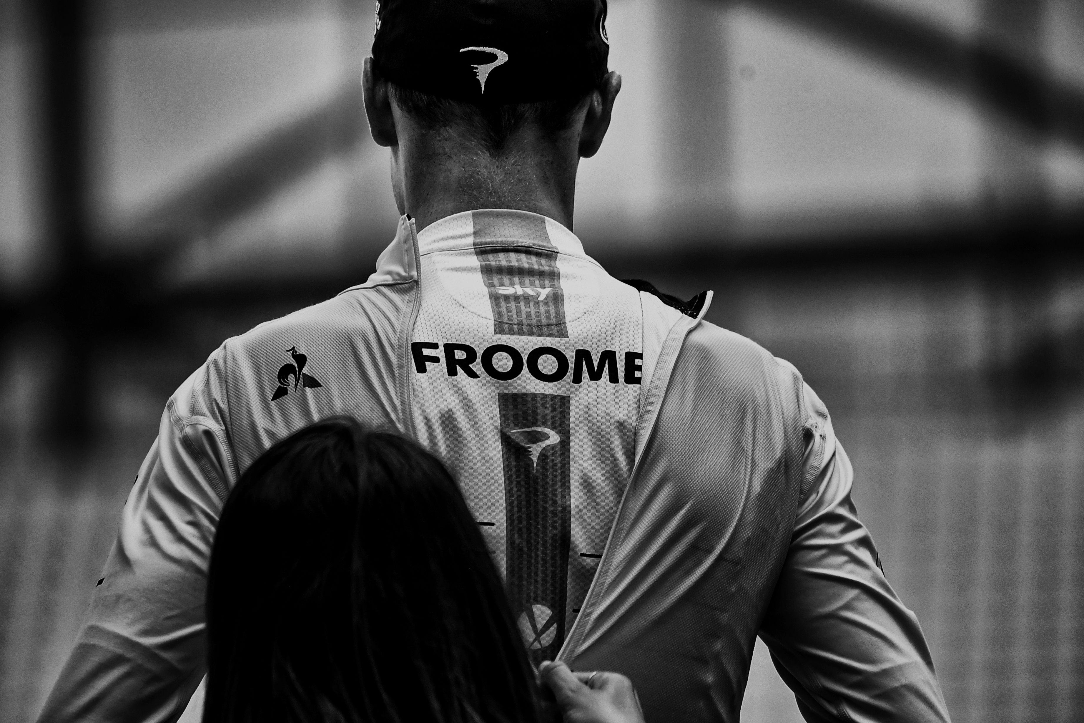 BLACK AND WHITE VERSION A hostess zips up the overall leader yellow jersey on Great Britain's Christopher Froome celebrating on the podium at the end of a 22,5 km individual time-trial, the twentieth stage of the 104th edition of the Tour de France cycling race on July 22, 2017 in and around Marseille, southern France. / AFP PHOTO / JEFF PACHOUD (Photo credit should read JEFF PACHOUD/AFP/Getty Images)